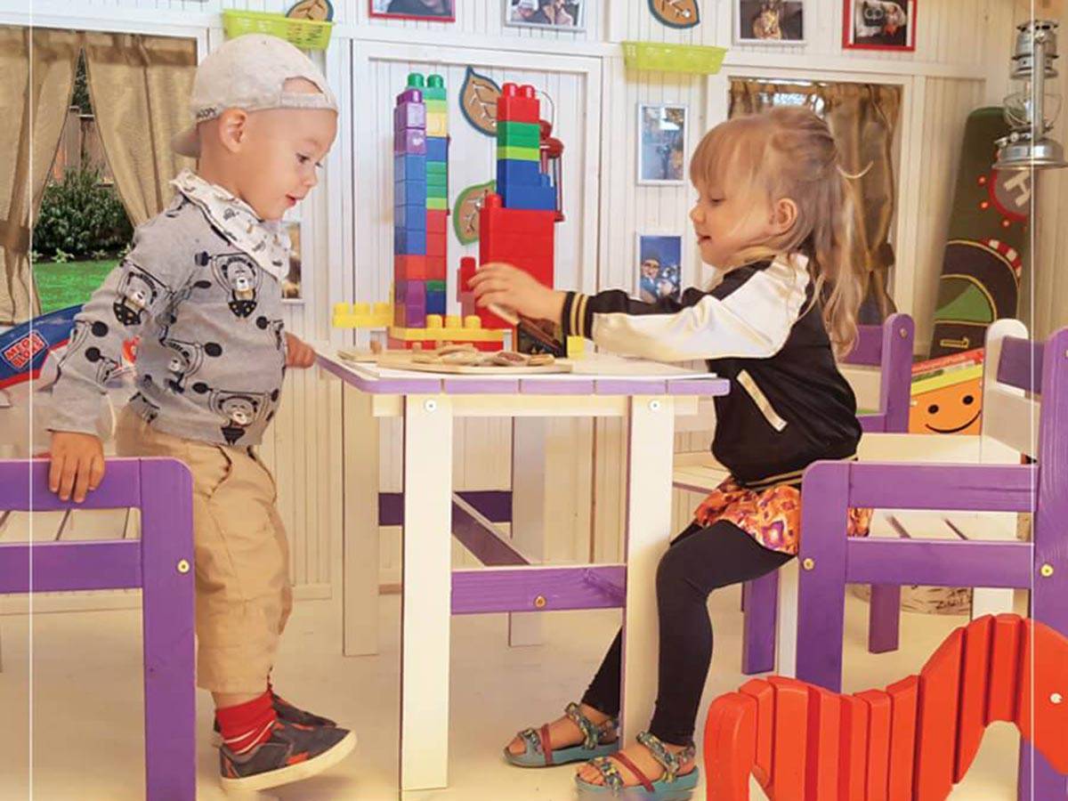 Kids playing inside of the Wooden Playhouse Classy Wicky by WholeWoodPlayhouses