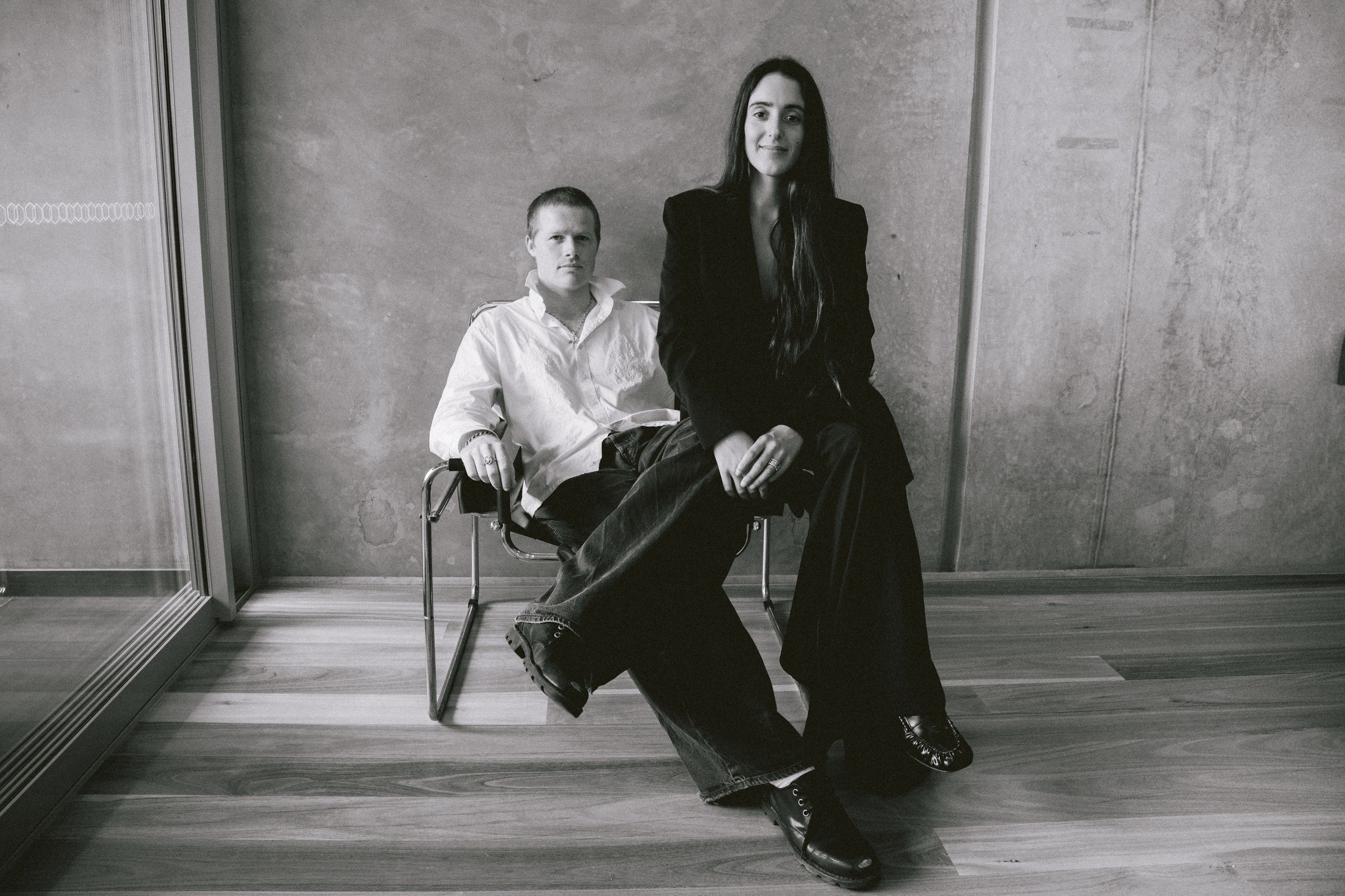 Black and white photo of a man sitting and a woman standing beside him.