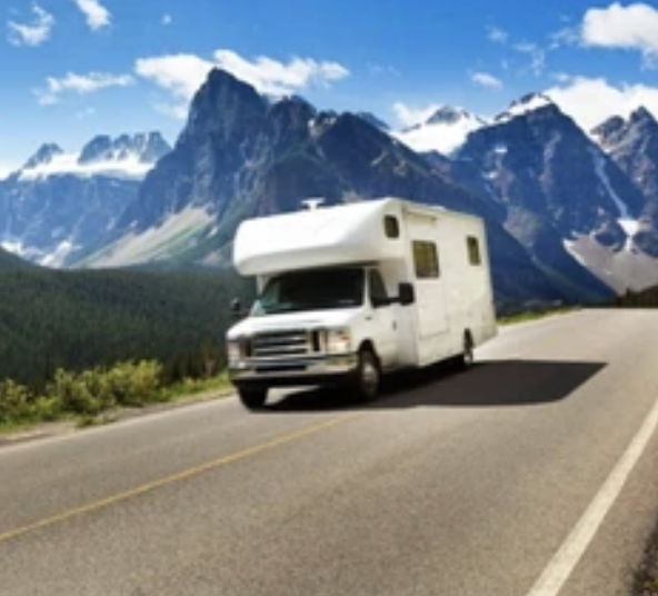A recreational vehicle driving on a road with mountains in the background.