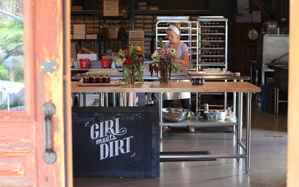 A few through the barn doors at Girl Meets Dirt Handpicked, into the kitchen. A staff person is arranging flowers on a table. 