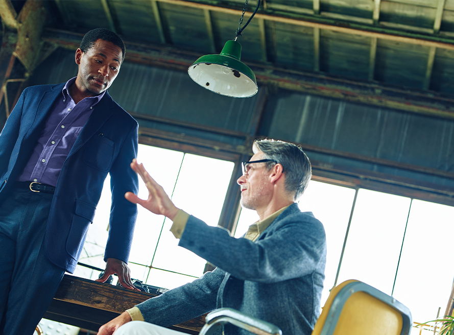 Two men engaged in conversation in a modern workspace.