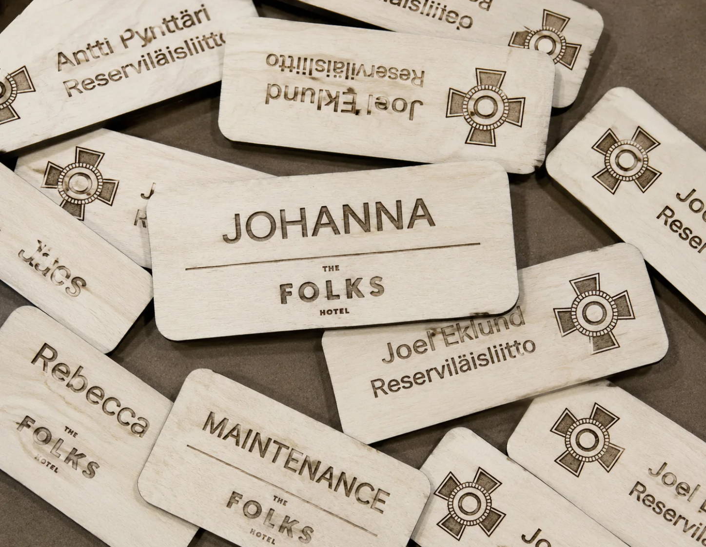 Puinen nimikyltti yrityksen logolla ja työntekijän nimellä