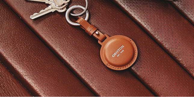 Brown leather keychain on a textured surface with keys.