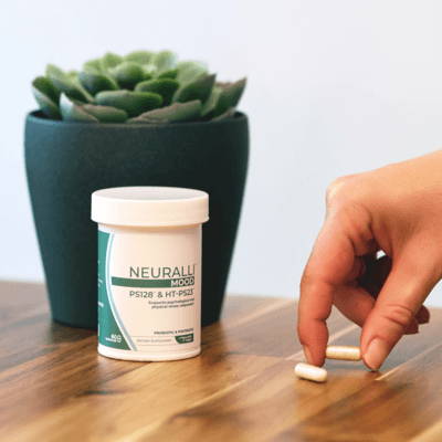 A hand reaching for pills next to a succulent plant.