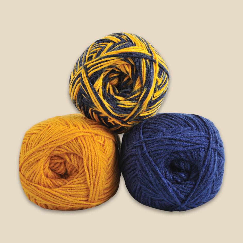 Three balls of Herrschners MVP yarn in yellow, blue, and multicolored.