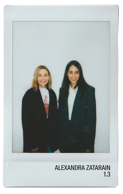 Two women smiling in oversized blazers, standing together against a plain background.