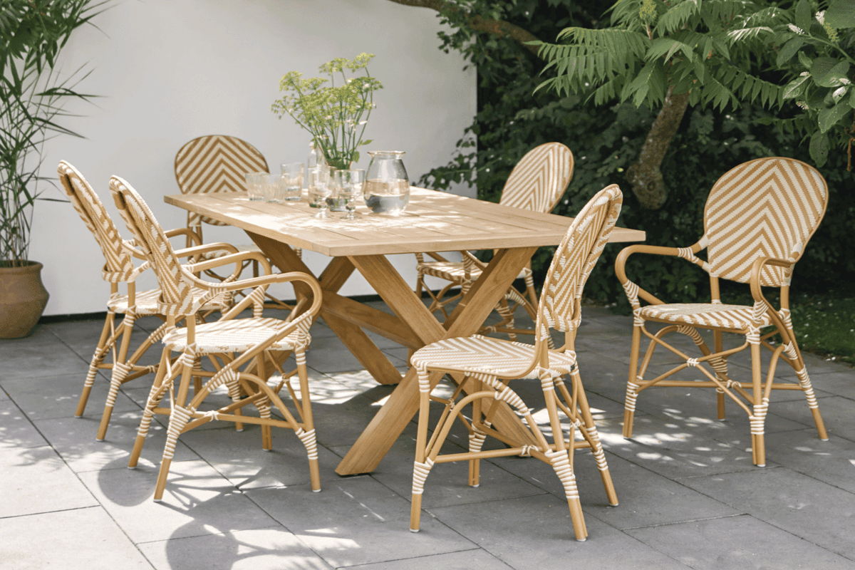 All-weather wicker dining chairs with a tan-and-white chevron weave arranged around a teak outdoor dining table.