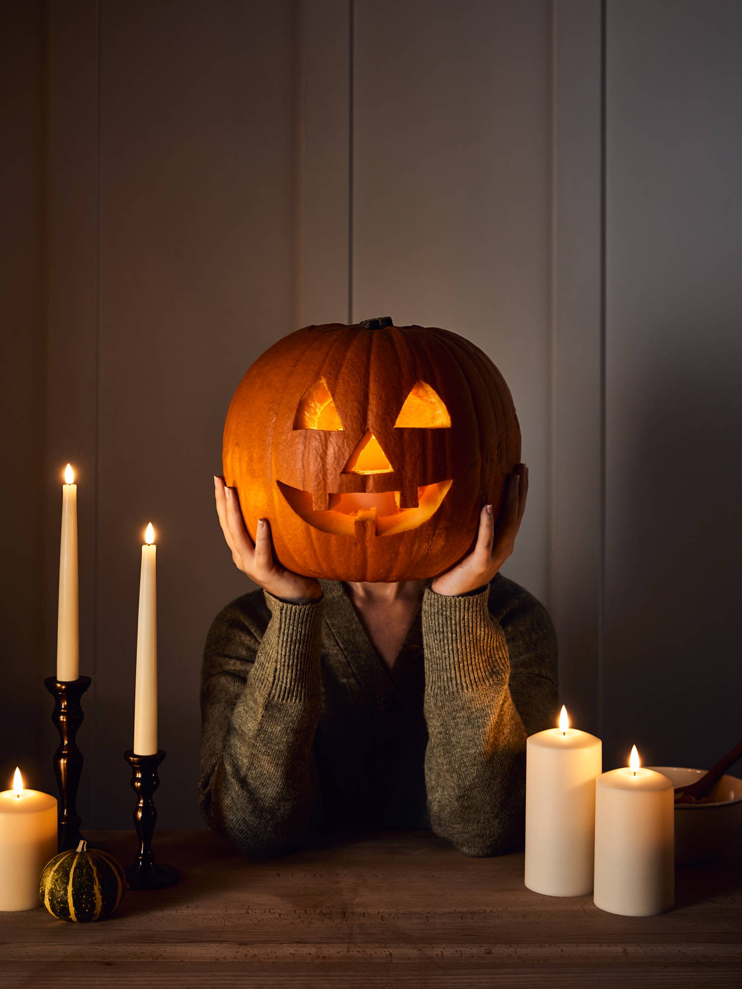 Person holding up completed and lit up pumpkin
