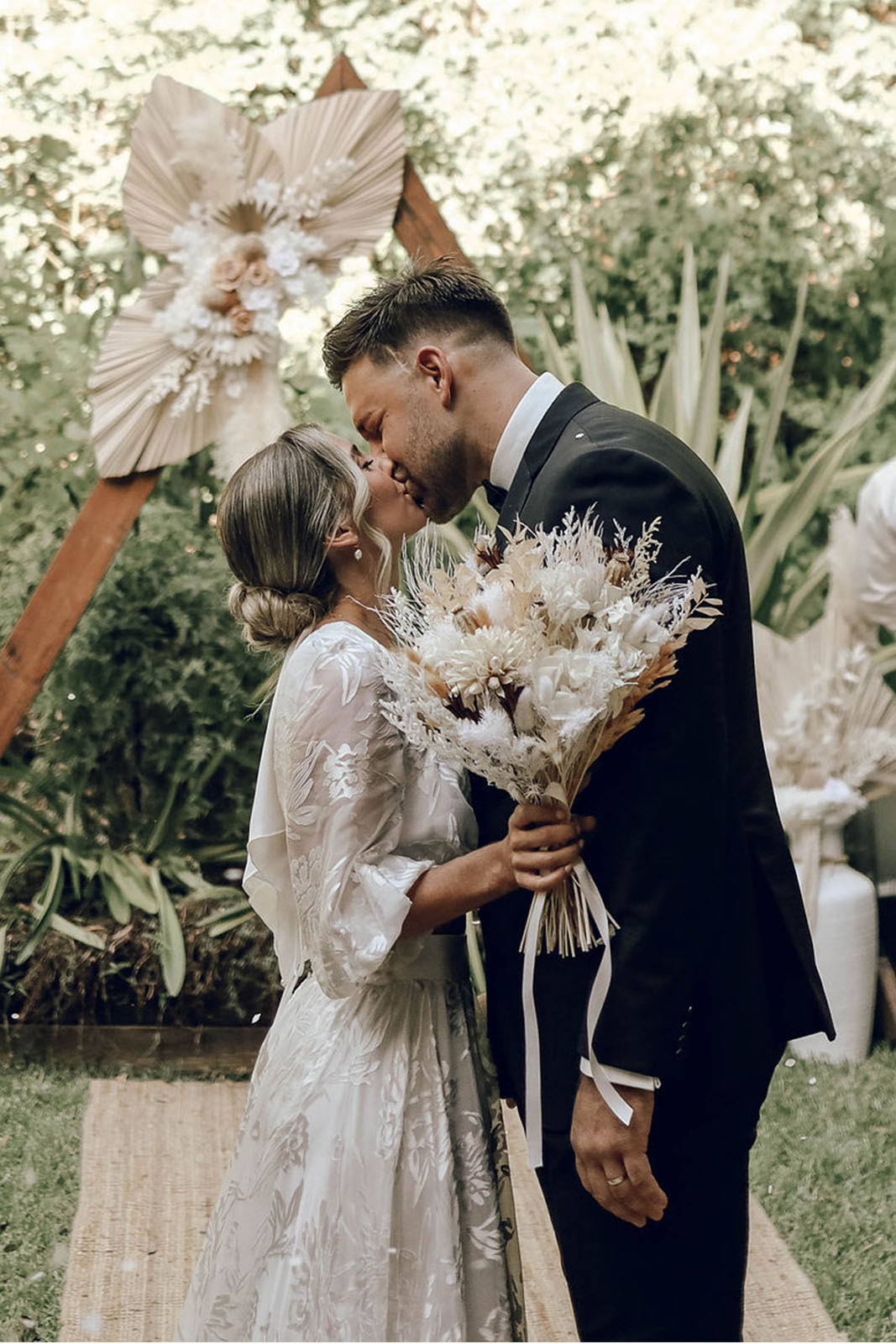 Bride and groom, sharing a romantic kiss while the bride is holding her wedding bouquet