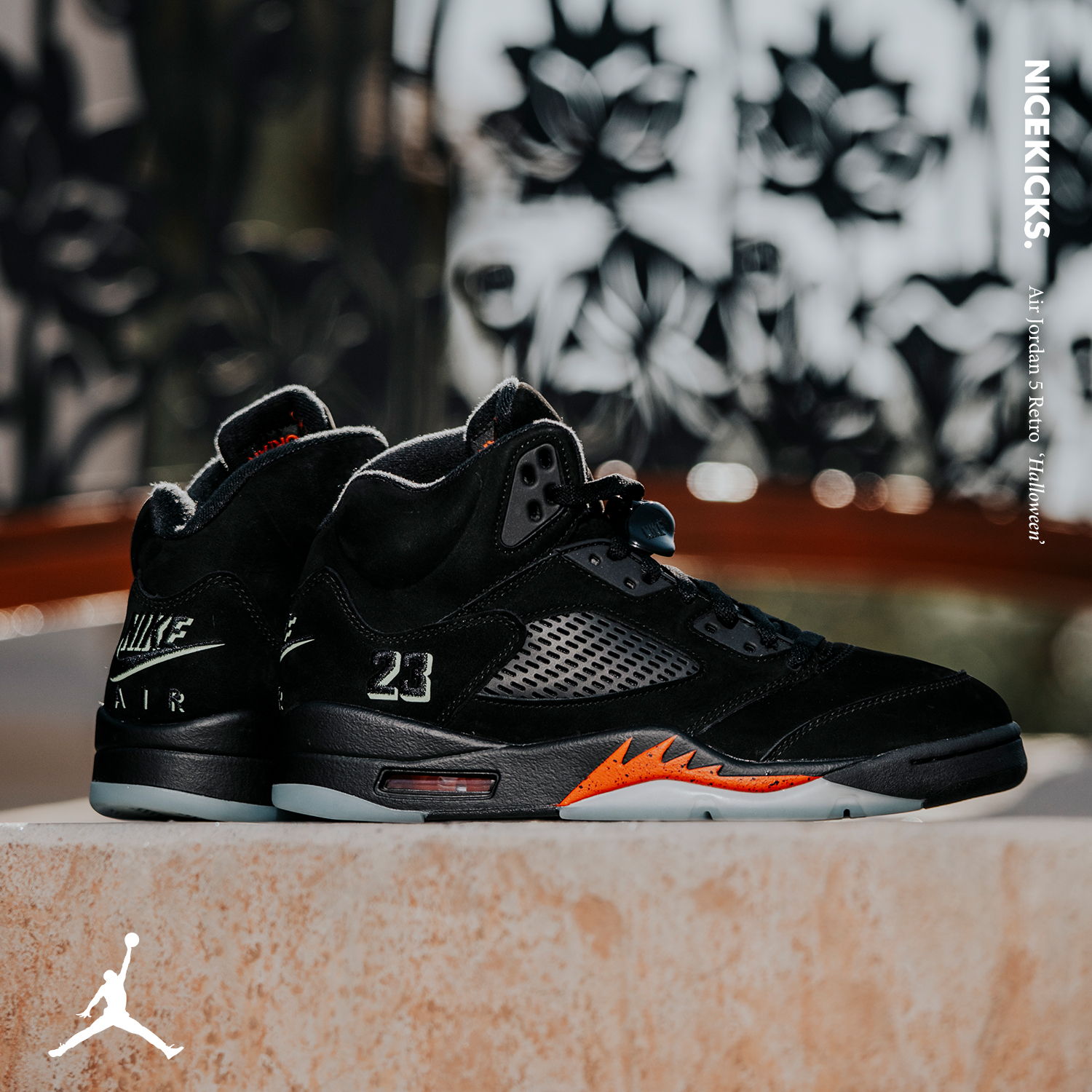 A pair of black and orange Air Jordan 5 sneakers on a surface.