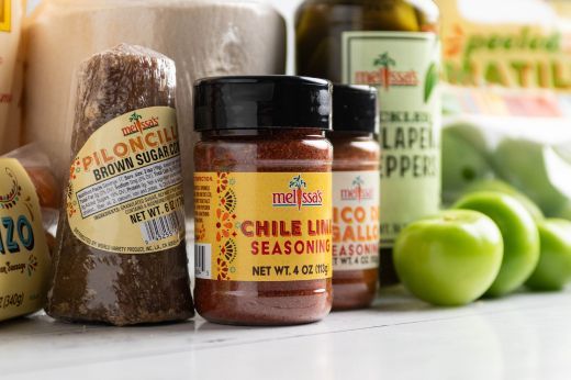Assorted spices, seasonings, and fresh produce on a kitchen counter.