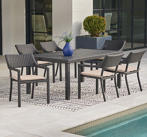 Outdoor dining set with six chairs and a table, situated by a pool.