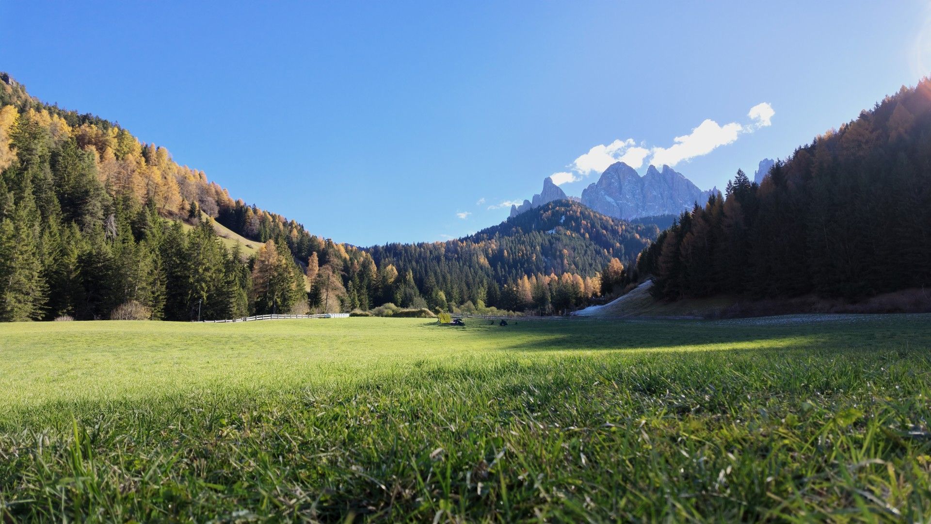 Scenic landscape with mountains, green fields, and blue sky.