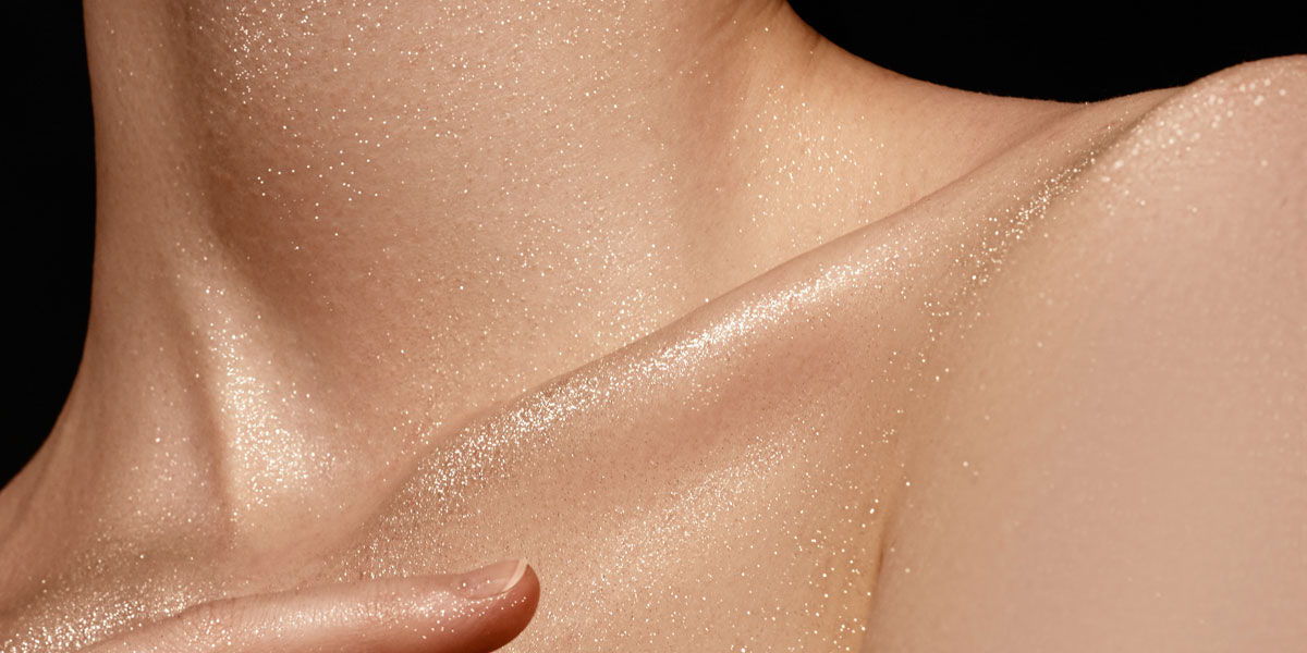 Close-up of a smooth, illuminated neck and shoulder against a dark background.
