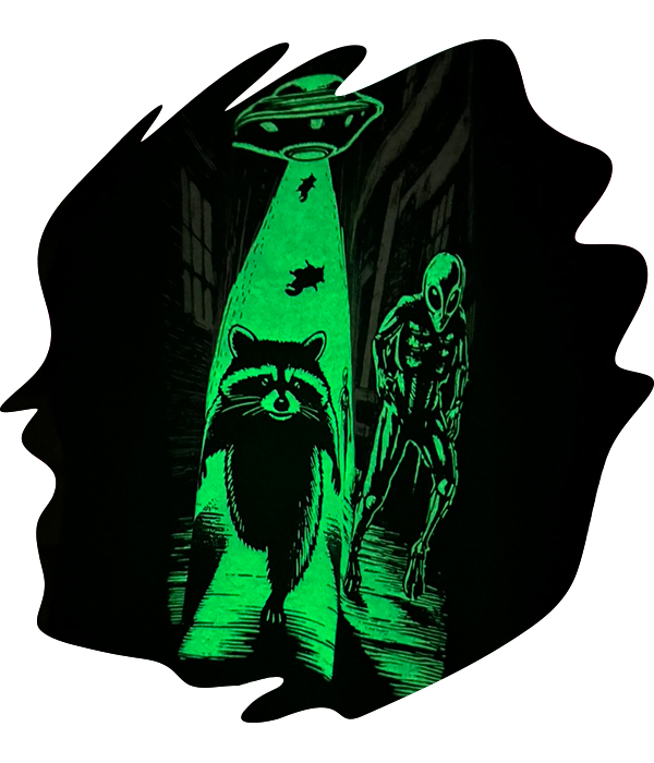 Black garment with glow-in-the-dark specialty ink print showing raccoon and alien scene illuminated in and alley with a glowing green effect