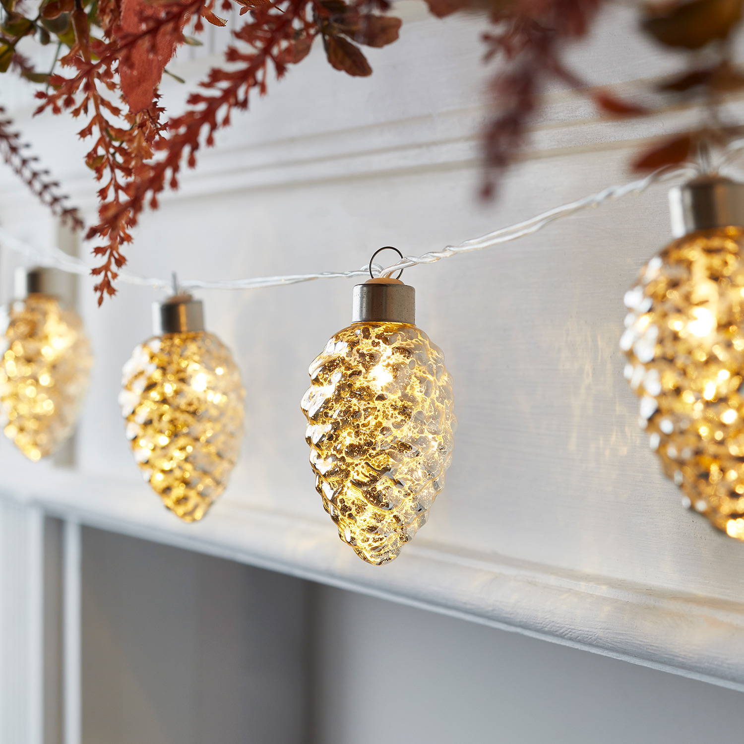 Pinecone fairy lights illuminated across mantel