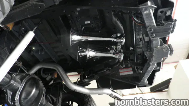 Two chrome train horns mounted to the undercarriage of Wicked Customs's Ford F250 in a shop