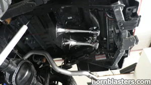 Two chrome train horns mounted to the undercarriage of Wicked Customs's Ford F250 in a shop