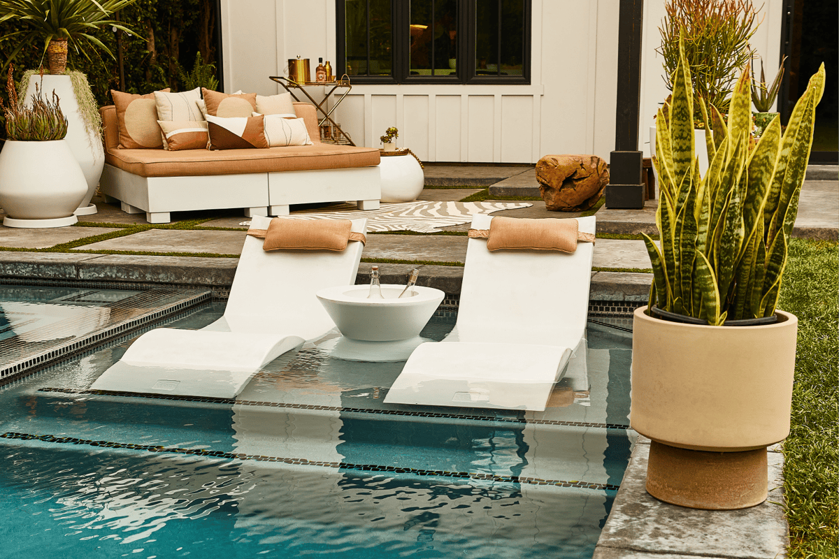 In-pool chaise loungers with an ice bucket for beverages on a tanning ledge with a daybed in the background. 