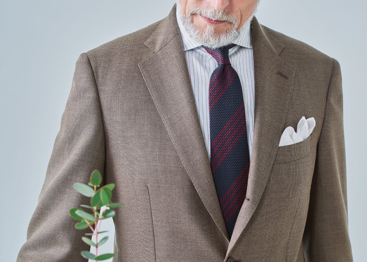 Man in a suit holding a small plant branch.