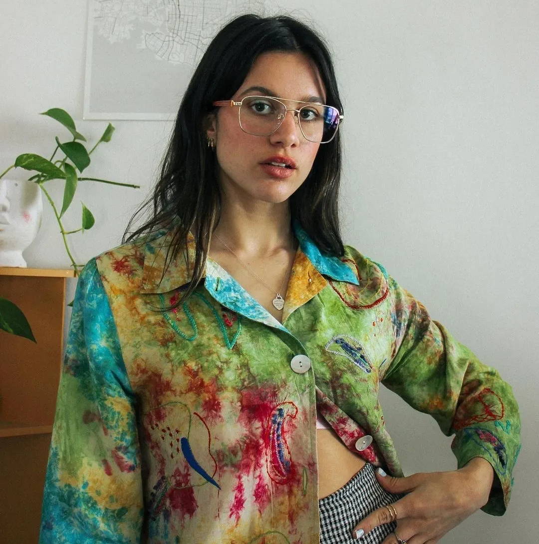 Woman wearing a funky shirt, checkered pants and Drive Gold, funky glasses in gold metal 