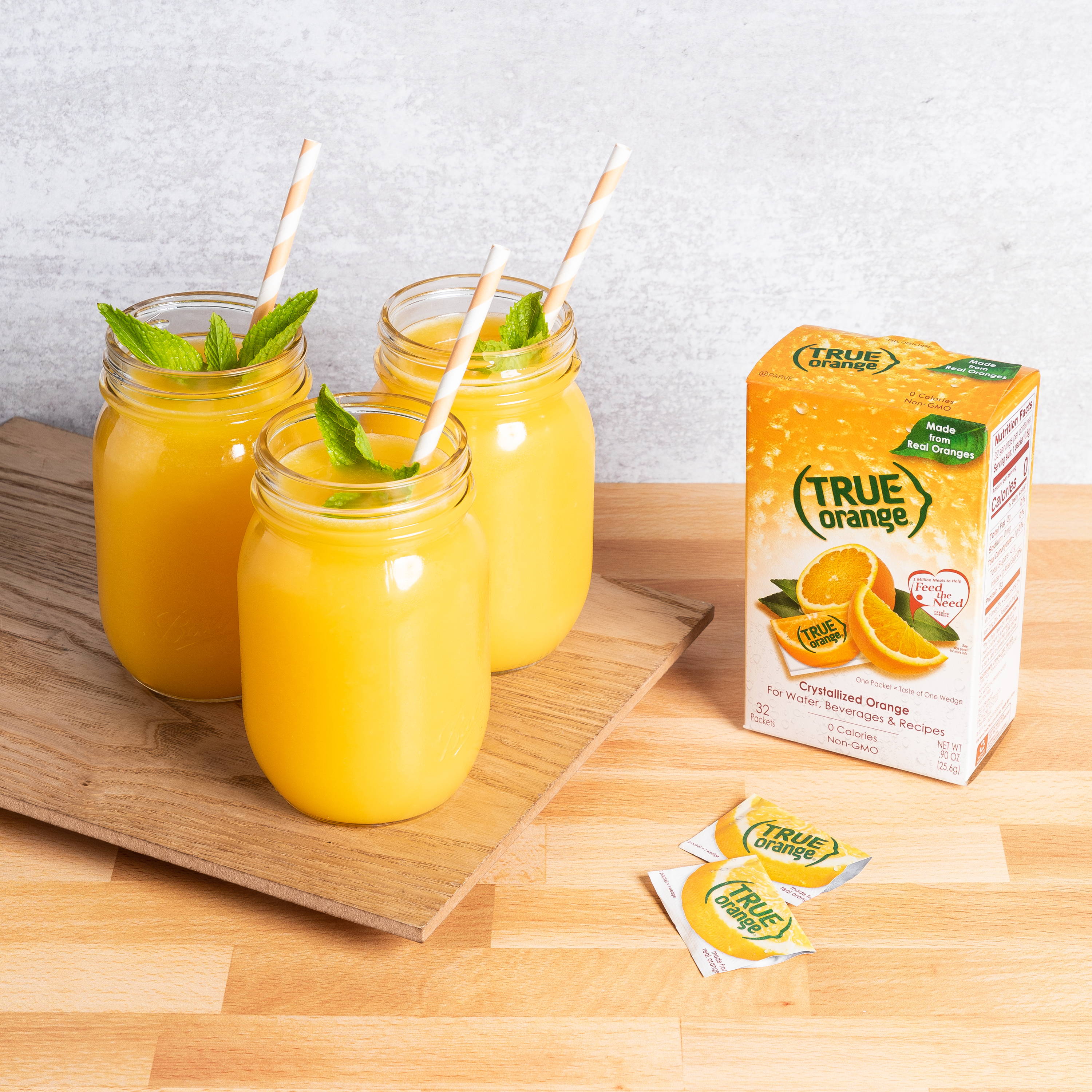 Box of true orange flavor packets with three jars of true orange drink with straws