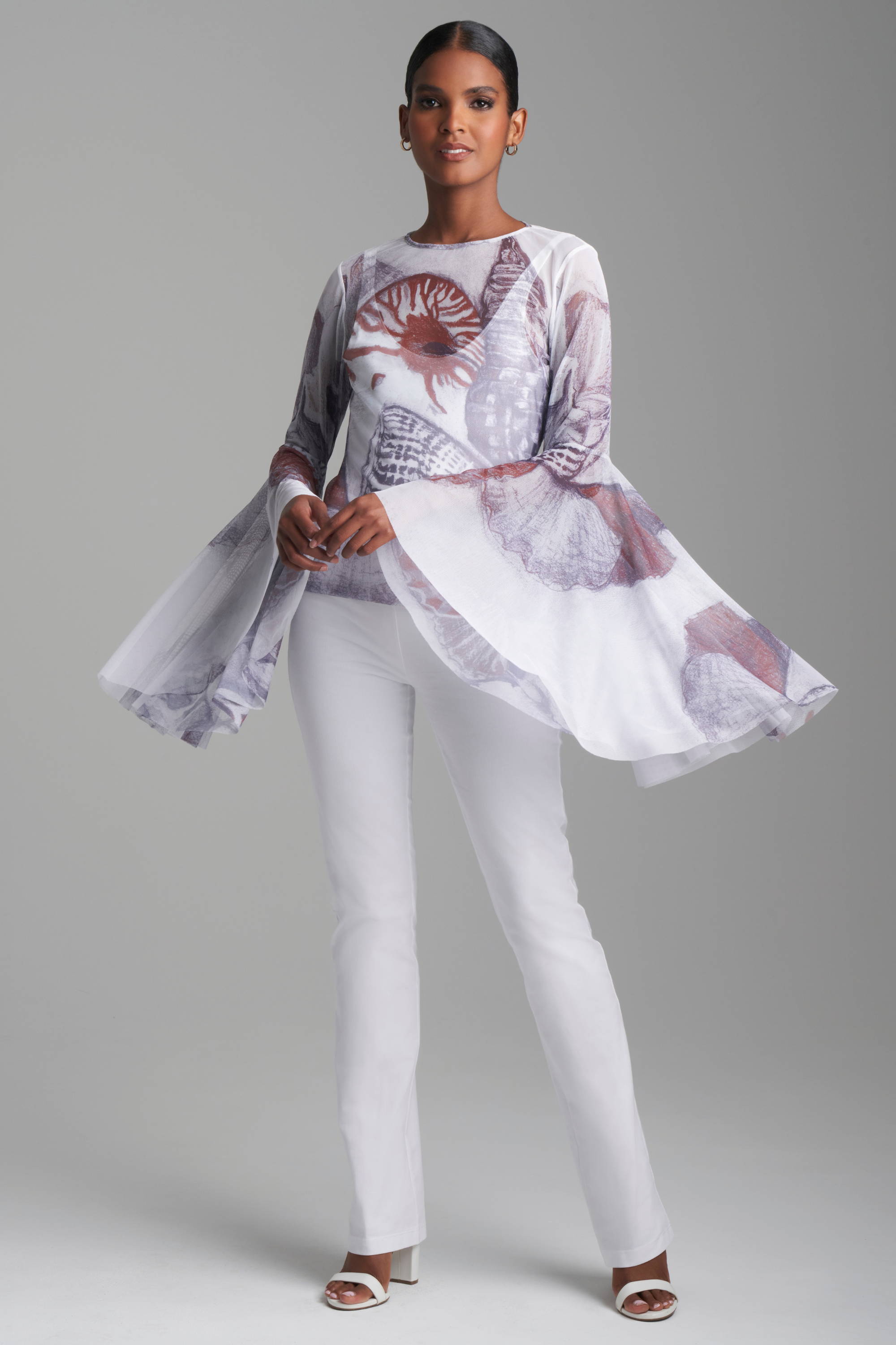 Woman wearing mesh top with flounce sleeves with white stretch cotton pants by Ala von Auersperg