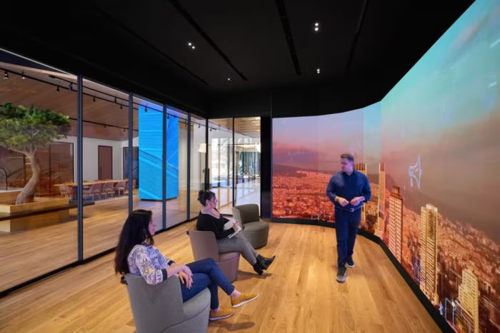 People in a modern room with large screens and a presentation.