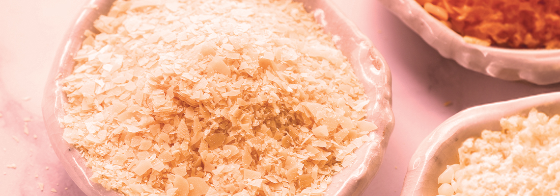 Bowls of different types of rice on a pink background.