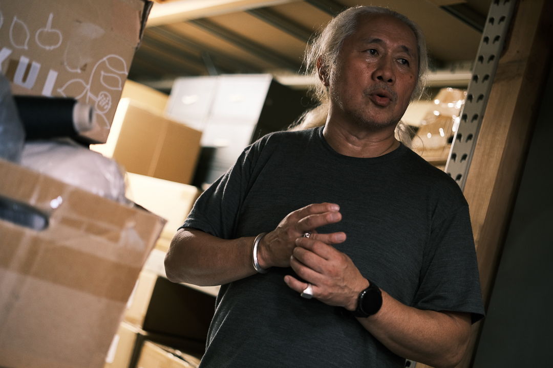 A man stands among boxes in a dimly lit storage area.