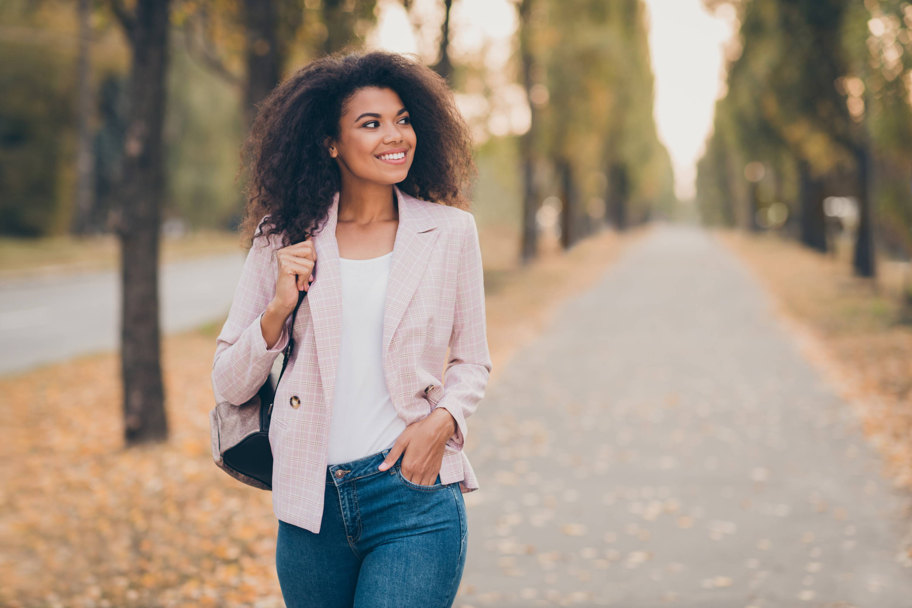 Stylish woman smiling and walking down street