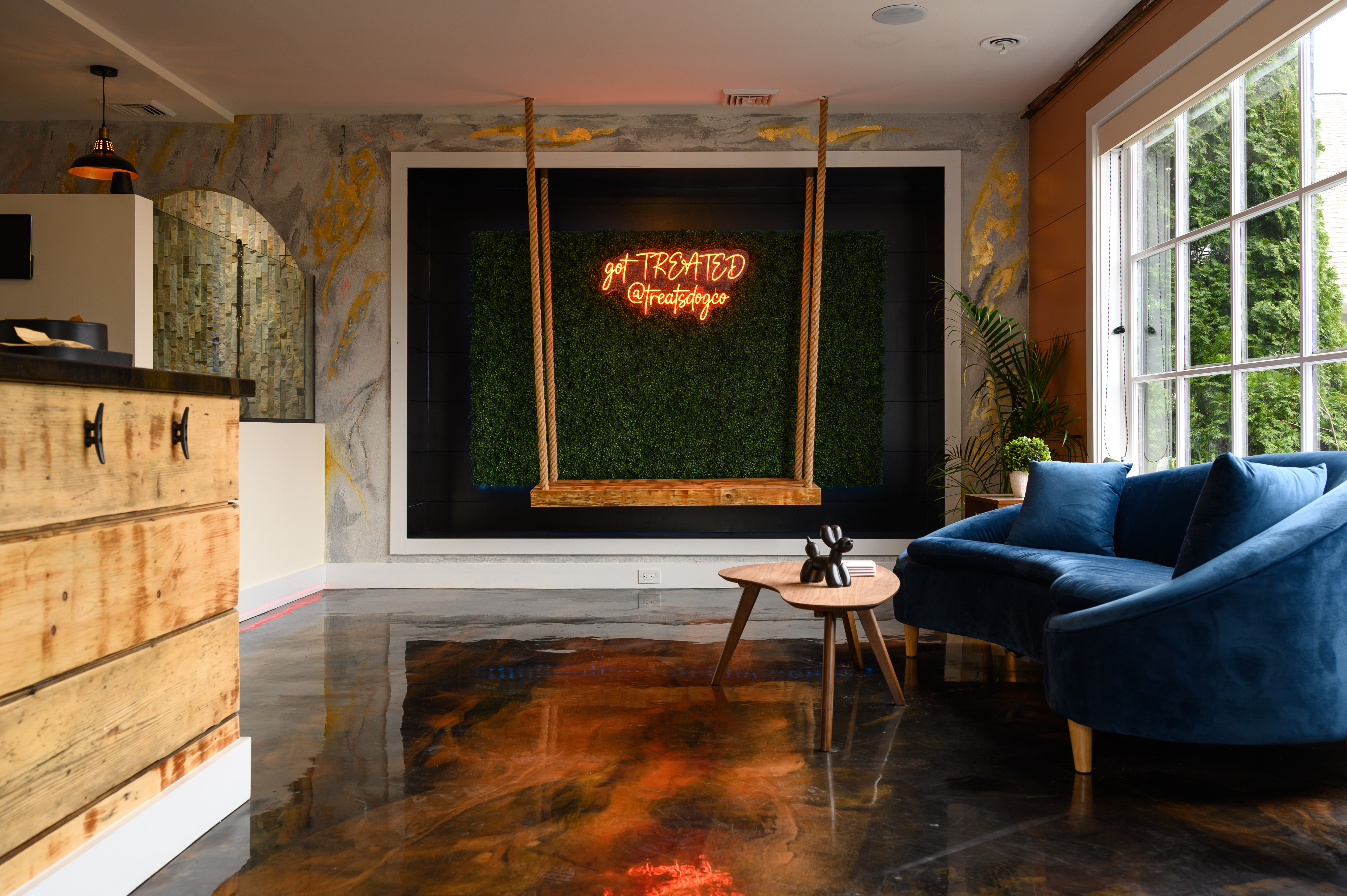 Treated Groom Spa reception with blue seating, a wooden swing, and the illuminated salon sign