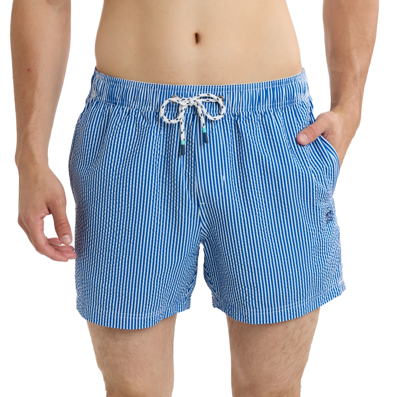 Man wearing blue striped swim shorts with hands in pockets.