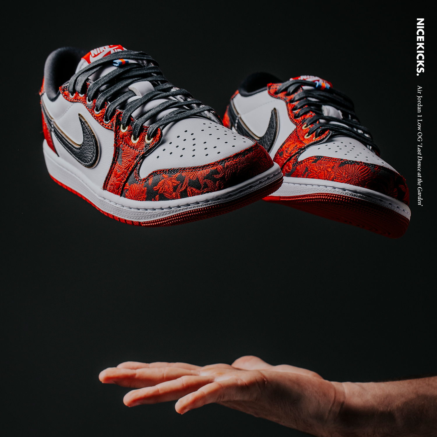 A hand reaching up to catch floating sneakers against a dark background.