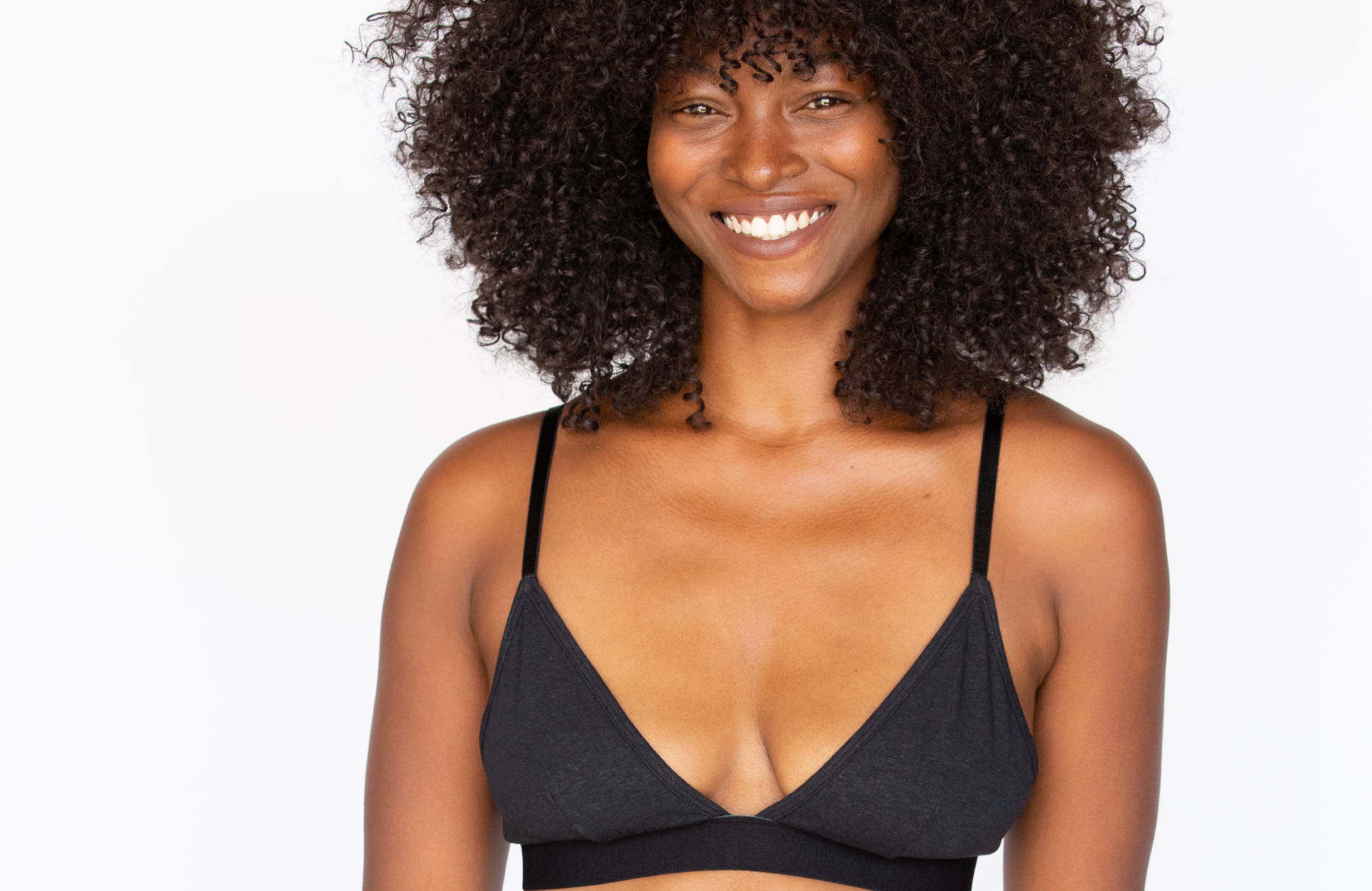 Smiling woman who knows how to tighten bra strap wearing a black triangle bralette with her hands at her side