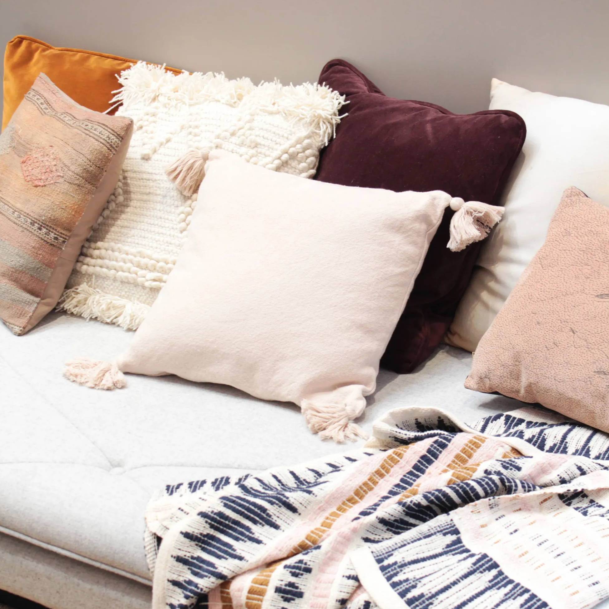 A cosy sofa setting with layered cushions, blankets and deep autumn tones.