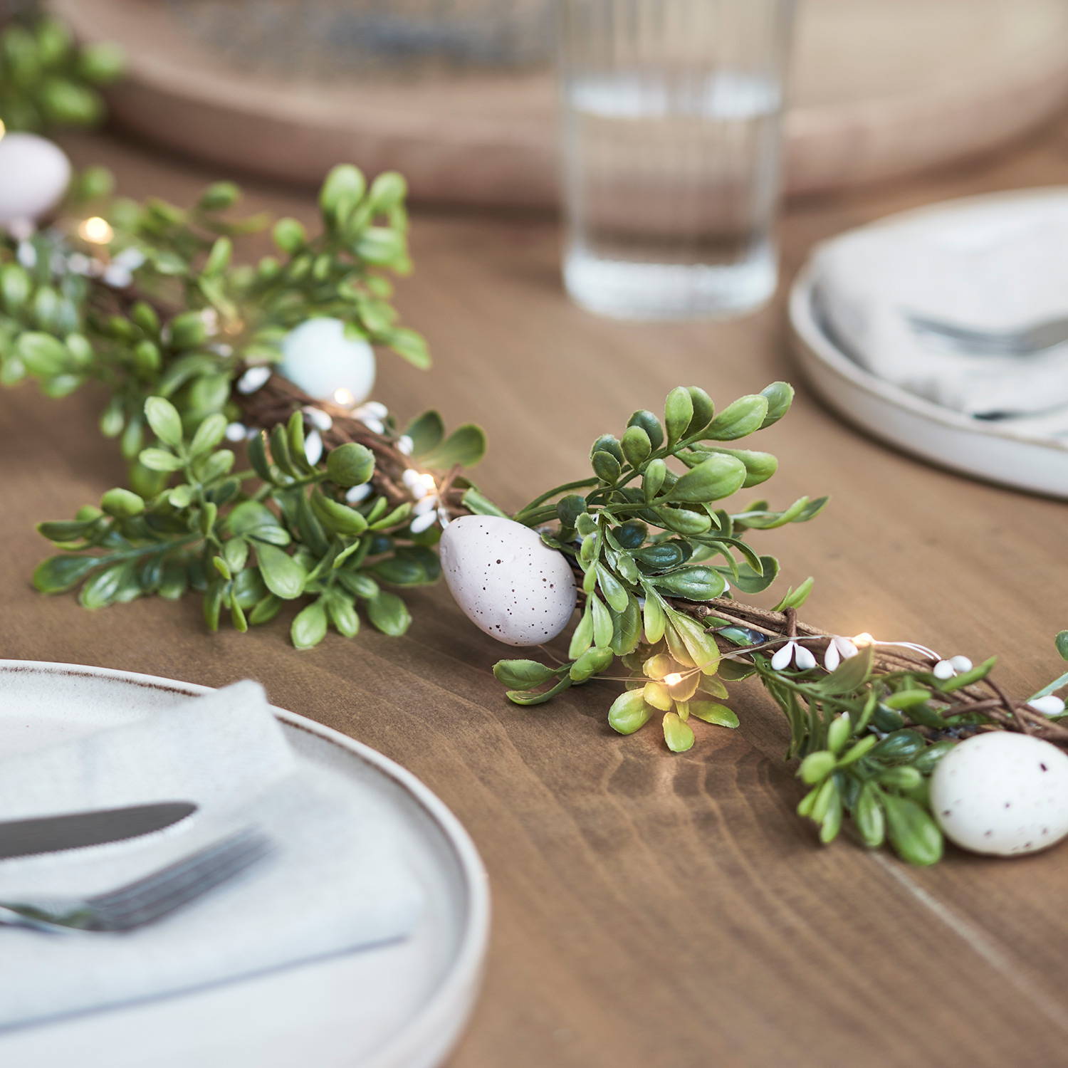 An Easter egg garland running along a dinning table as part of an Easter display.