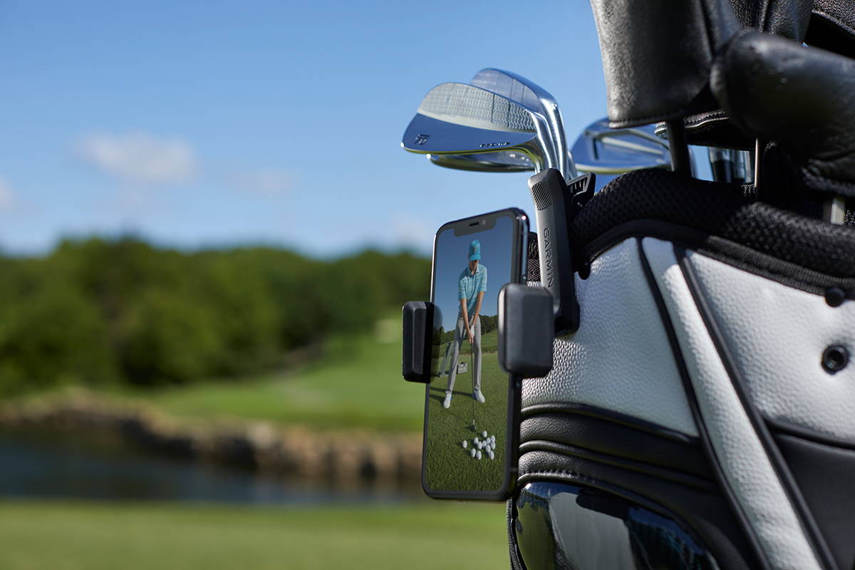 A smartphone with the Garmin Golf app on it attached to a golf bag on the golf course