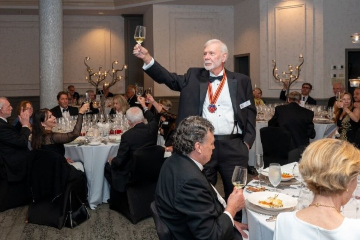 A man toasts at a formal dinner with guests in attendance.