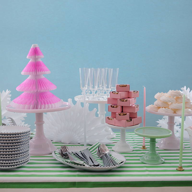 A vibrant christmas laid table, featuring a pink neon tree on a green and white striped tablecloth.