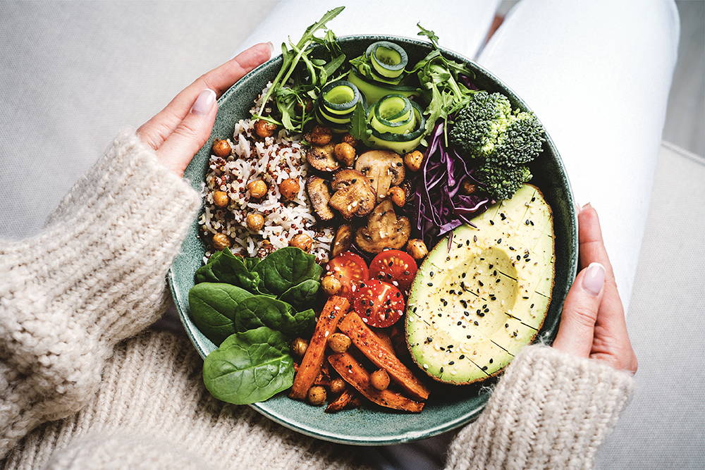 Woman sitting with vegan plant-based buddha bowl. 