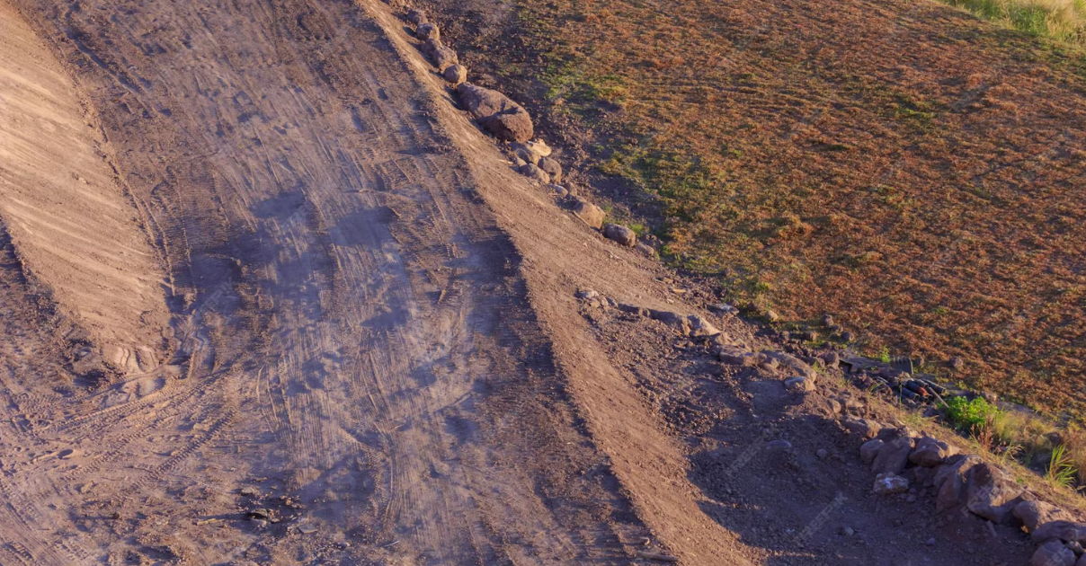Aerial view of a dirt path beside a grassy field.