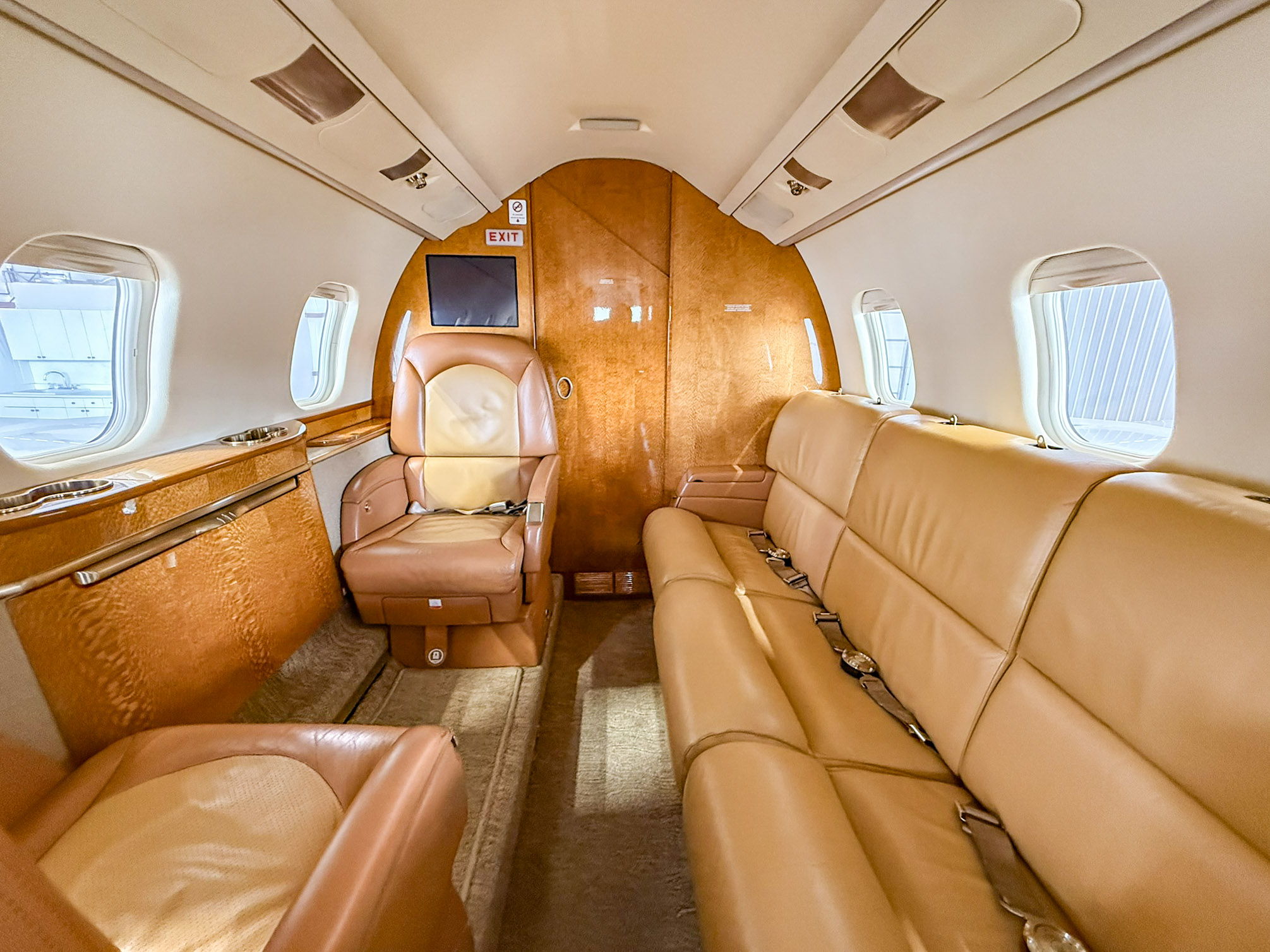 Interior of a private jet with leather seating and wooden accents.