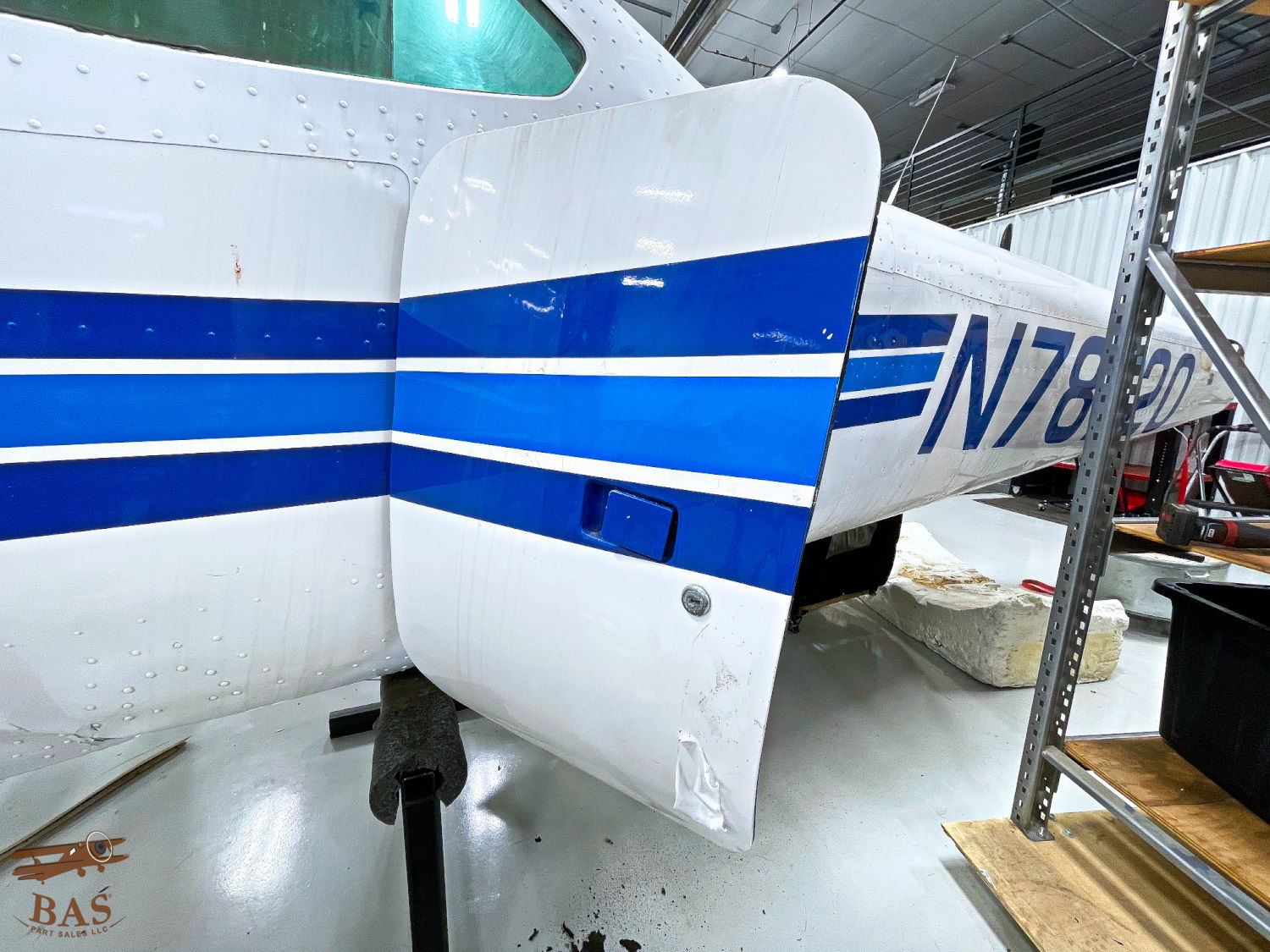 Close-up of an aircraft wing with blue stripes in a hangar.