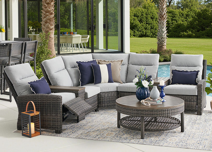 Outdoor seating area with a sectional sofa, coffee table, and decorative pillows.