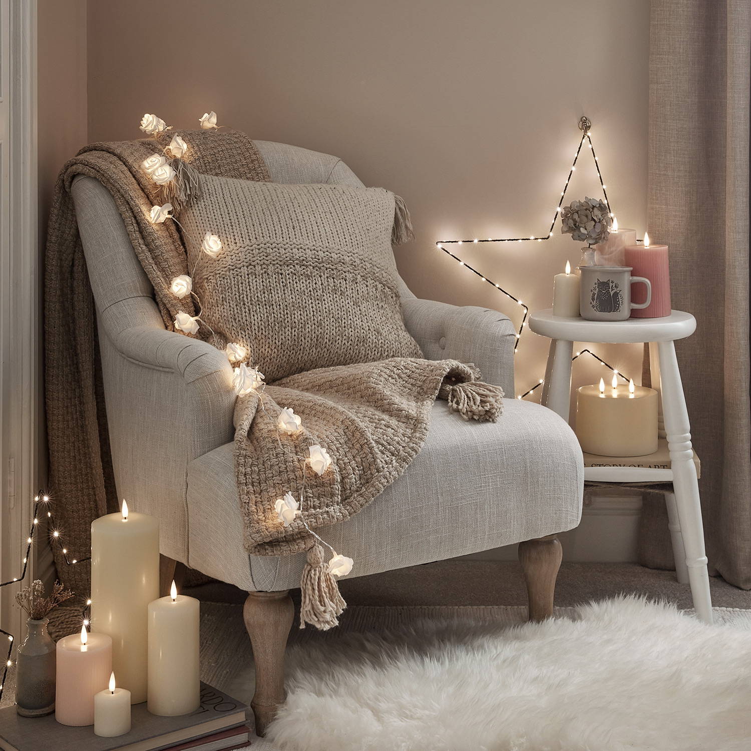 An armchair with a blanket and cushions with fairy lights, LED candles and a star light.