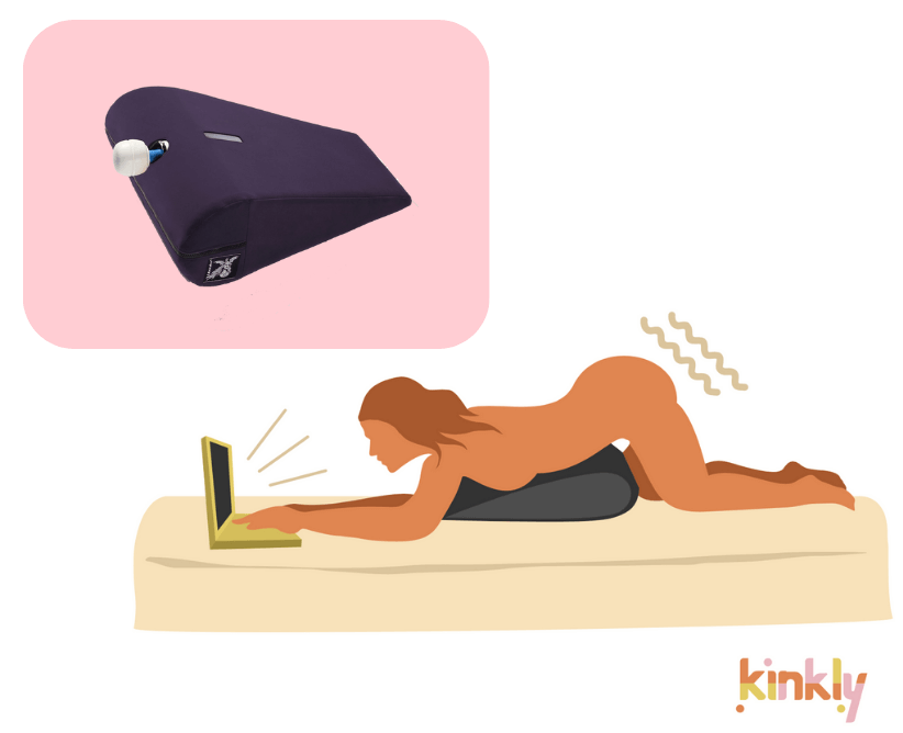 Liberator Axis with a wand massager shown next to an illustrated Browse and Buzz position. A solo person is laying down on their stomach. A triangular piece of sex furniture is propped underneath them, holding a vibrator between their thighs. The person uses their laptop with both hands as the sex furniture is holding the vibrator in place for them. | Kinkly Shop