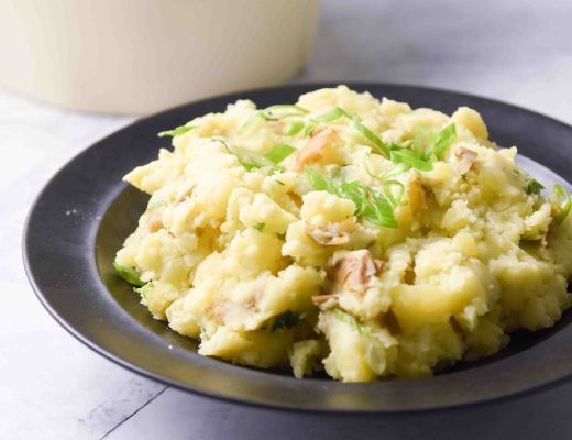 A plate of creamy mashed potatoes garnished with herbs.