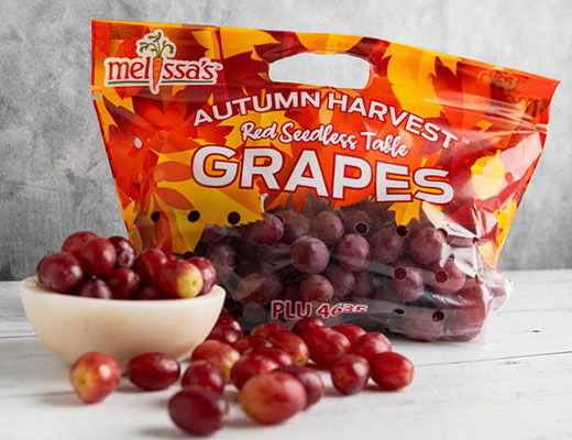 Bag of grapes with autumn-themed packaging and fresh grapes on a table.