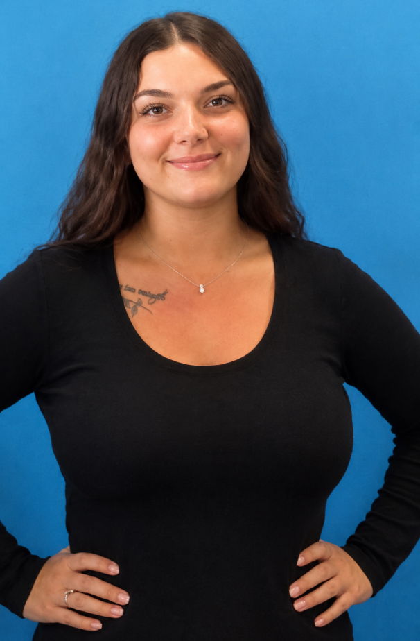 Smiling woman with long hair wearing a black shirt against a blue background.